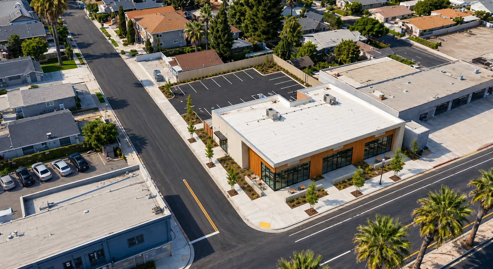 Aerial view of a single-story commercial pavilion with glass storefront and rear surface parking