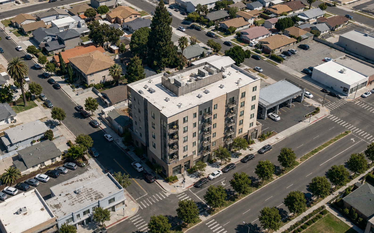 Aerial view of a six-story residential mid-rise with stacked balconies and a ground-floor lobby on the corner